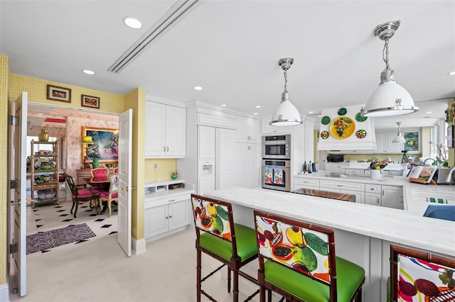 kitchen featuring decorative light fixtures, white cabinets, and a breakfast bar