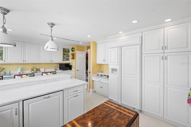 kitchen featuring white cabinetry, paneled built in refrigerator, light tile floors, and pendant lighting