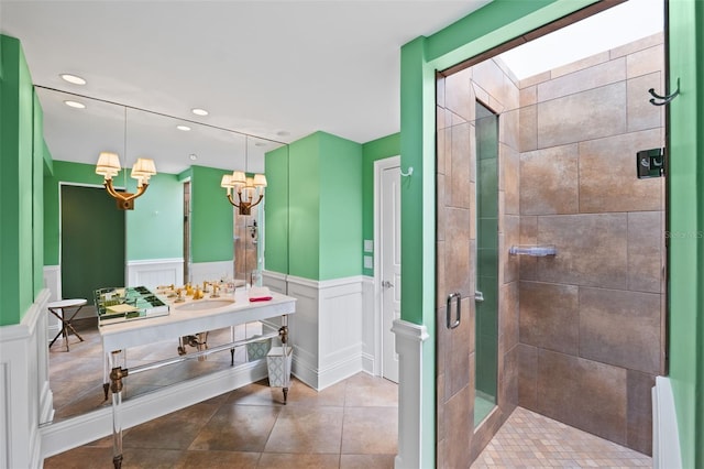 bathroom featuring tile flooring, a shower with door, an inviting chandelier, a skylight, and vanity