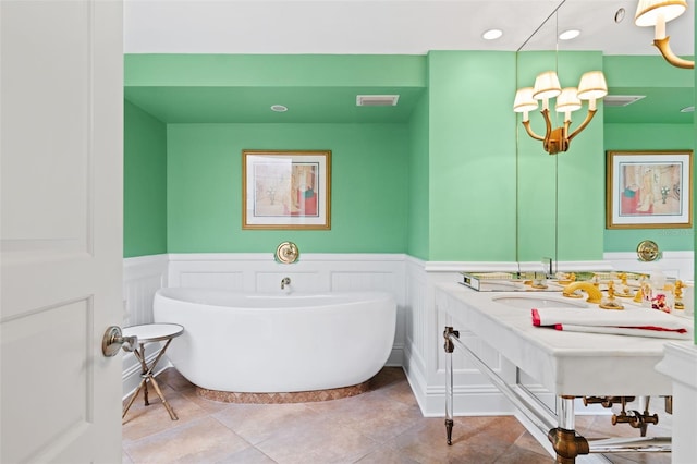 bathroom featuring a notable chandelier, vanity with extensive cabinet space, a washtub, and tile floors