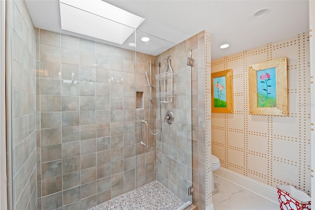 bathroom featuring a shower with shower door, toilet, and a skylight