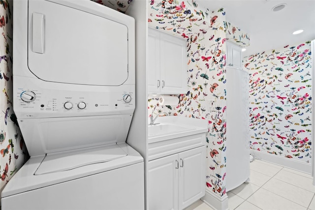 clothes washing area featuring stacked washer / dryer, sink, and light tile flooring