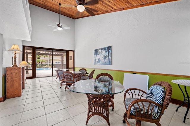 tiled dining space with a high ceiling, wood ceiling, and ceiling fan