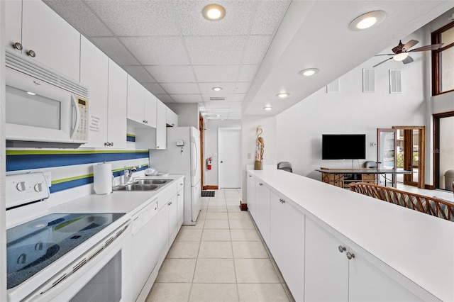 kitchen with white appliances, ceiling fan, a paneled ceiling, and white cabinetry