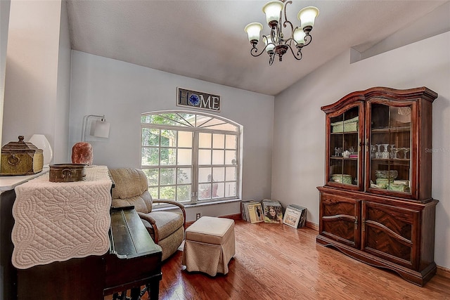 sitting room featuring a notable chandelier, hardwood / wood-style floors, and lofted ceiling