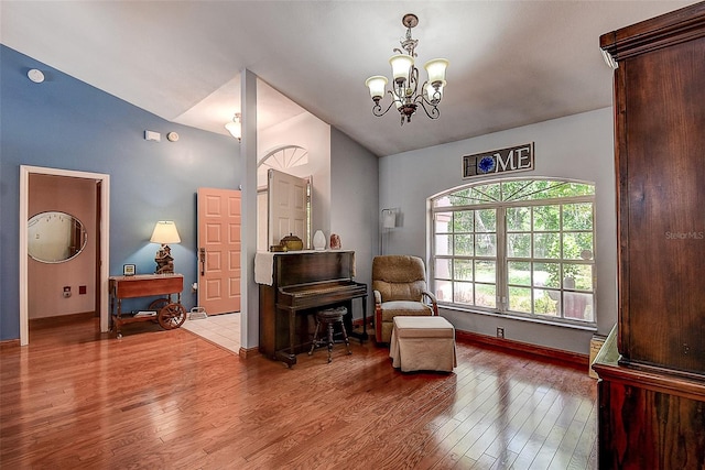 living area with hardwood / wood-style flooring, lofted ceiling, and an inviting chandelier