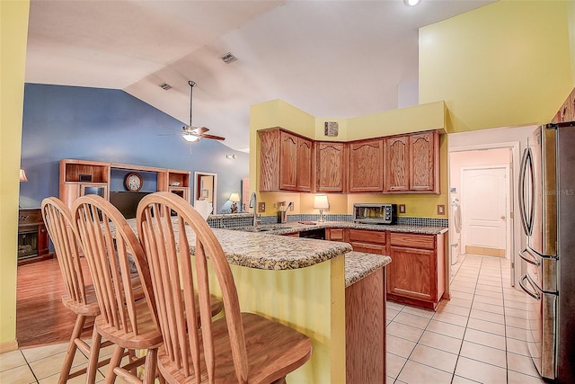 kitchen with stainless steel refrigerator, sink, light tile flooring, and kitchen peninsula