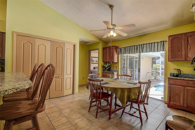 dining room featuring ceiling fan, light tile flooring, a textured ceiling, and lofted ceiling