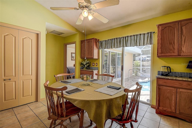 dining space featuring ceiling fan, lofted ceiling, and light tile floors