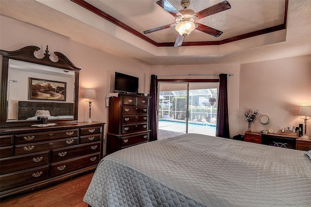 bedroom with ceiling fan, a raised ceiling, a textured ceiling, access to exterior, and hardwood / wood-style flooring