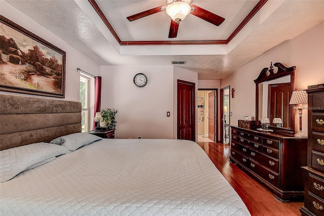 bedroom featuring ceiling fan, a raised ceiling, dark hardwood / wood-style flooring, and a textured ceiling