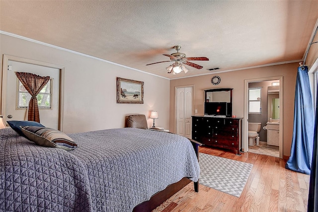 bedroom featuring crown molding, a textured ceiling, hardwood / wood-style flooring, ensuite bathroom, and ceiling fan