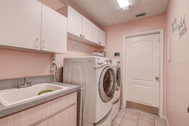 laundry area featuring sink, washer and dryer, light tile flooring, and cabinets