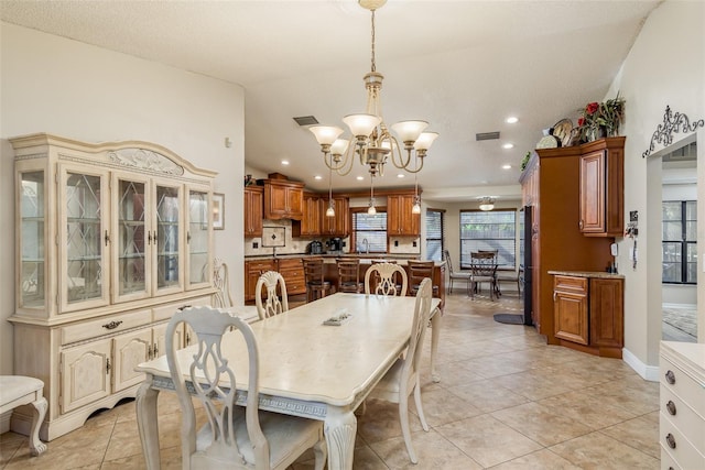 tiled dining room with lofted ceiling, sink, and a chandelier