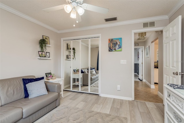 living room with ceiling fan, ornamental molding, light hardwood / wood-style floors, and a textured ceiling