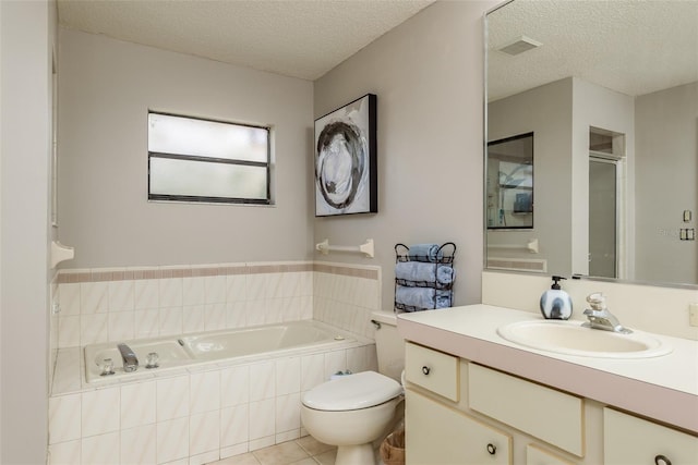 bathroom with tile patterned flooring, vanity, tiled bath, and a textured ceiling