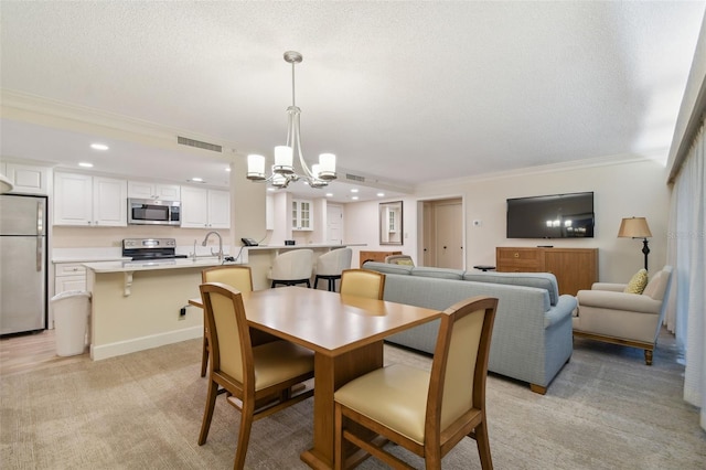 carpeted dining space featuring a textured ceiling, sink, a notable chandelier, and ornamental molding