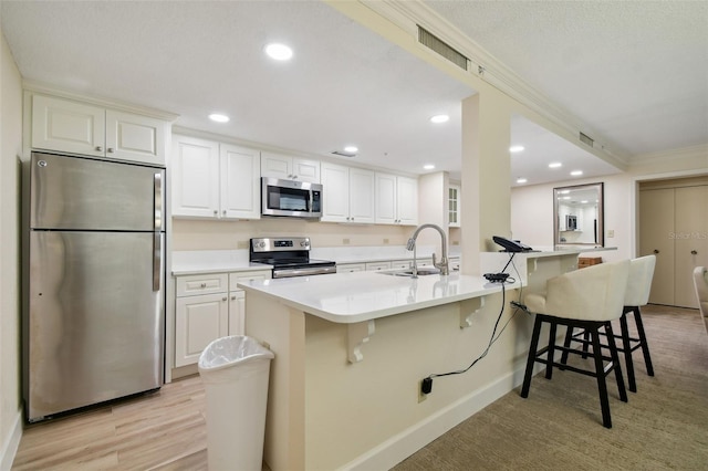 kitchen featuring appliances with stainless steel finishes, sink, light hardwood / wood-style floors, and a kitchen bar