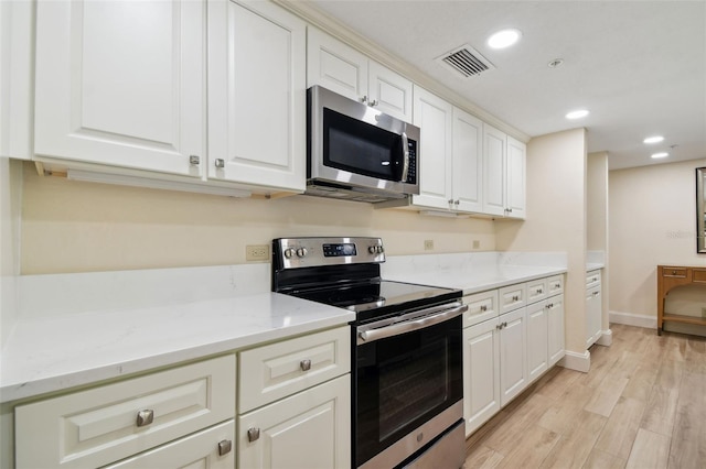 kitchen featuring appliances with stainless steel finishes, light hardwood / wood-style floors, white cabinetry, and light stone counters