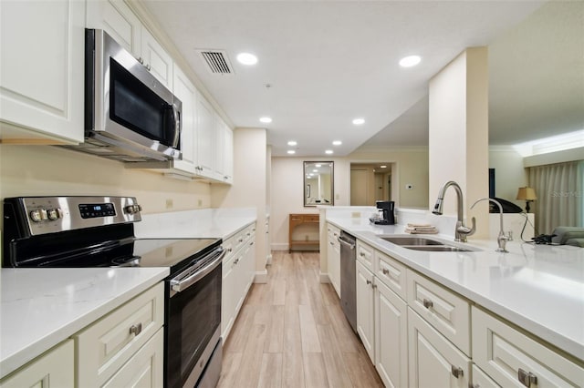 kitchen featuring appliances with stainless steel finishes, sink, white cabinetry, crown molding, and light hardwood / wood-style flooring