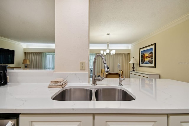 kitchen with hanging light fixtures, white cabinets, ornamental molding, an inviting chandelier, and sink