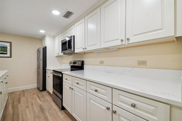 kitchen with light hardwood / wood-style floors, stainless steel appliances, white cabinets, and light stone countertops