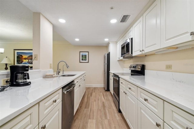 kitchen with stainless steel appliances, light hardwood / wood-style floors, white cabinetry, sink, and ornamental molding