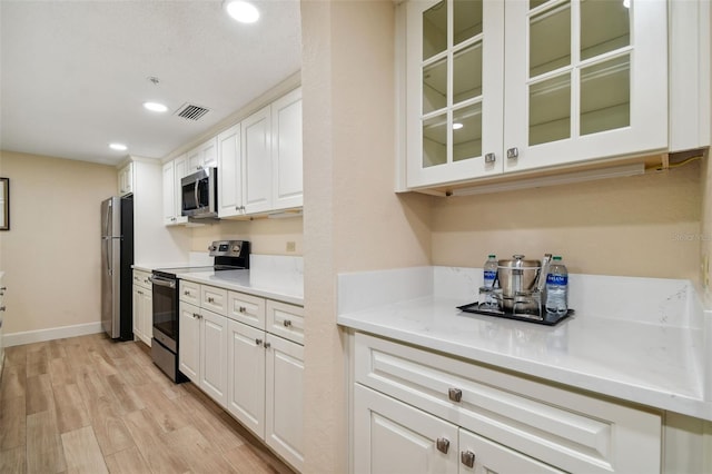 kitchen with light hardwood / wood-style flooring, stainless steel appliances, white cabinets, and light stone countertops