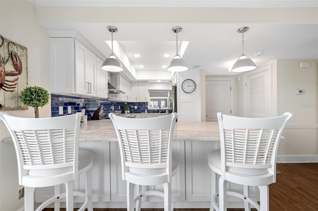 kitchen with backsplash, white cabinets, dark hardwood / wood-style floors, and decorative light fixtures