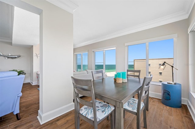 dining room featuring hardwood / wood-style flooring, a water view, and ornamental molding