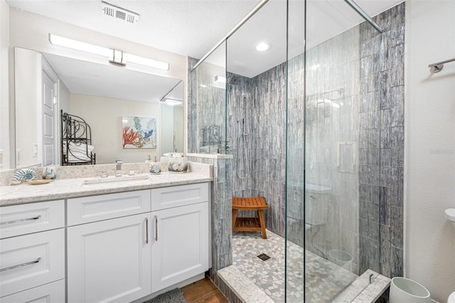 bathroom with tile patterned flooring, vanity, tiled shower, and a textured ceiling