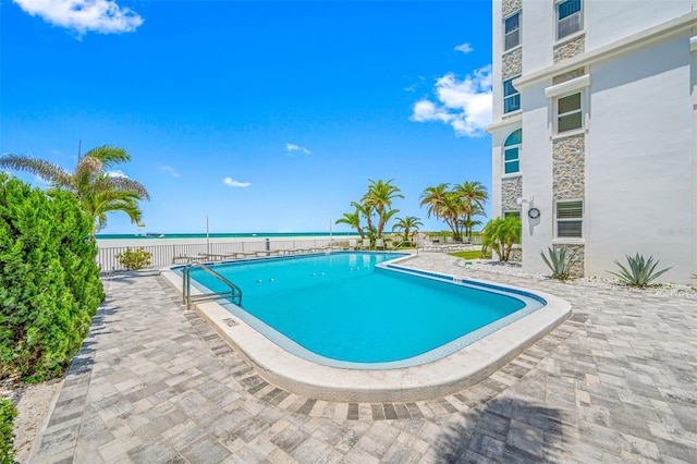 view of swimming pool featuring a water view and a patio