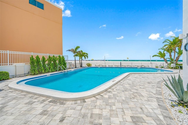 view of pool featuring a water view and a patio