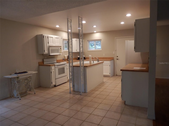 kitchen with light tile patterned floors, white appliances, a center island, and white cabinetry