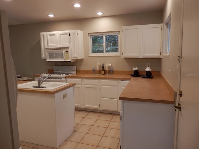 kitchen with white cabinets, range, light tile patterned floors, and sink