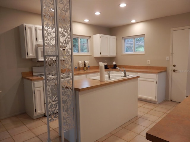 kitchen featuring white cabinets, a healthy amount of sunlight, light tile patterned floors, and sink