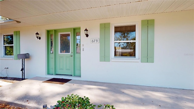 doorway to property featuring a porch and stucco siding