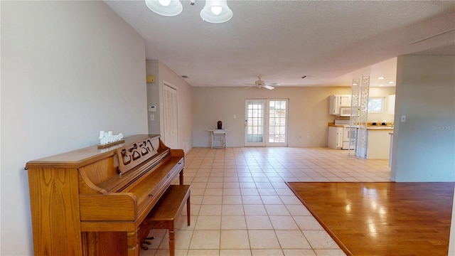 interior space featuring ceiling fan, a textured ceiling, and light tile patterned floors