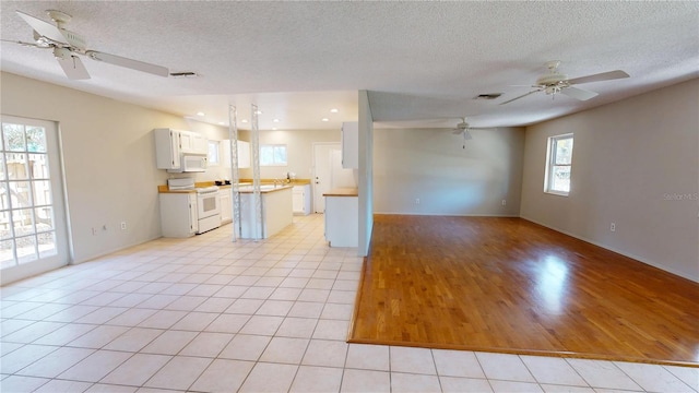 kitchen featuring white appliances, visible vents, a kitchen island, open floor plan, and light countertops