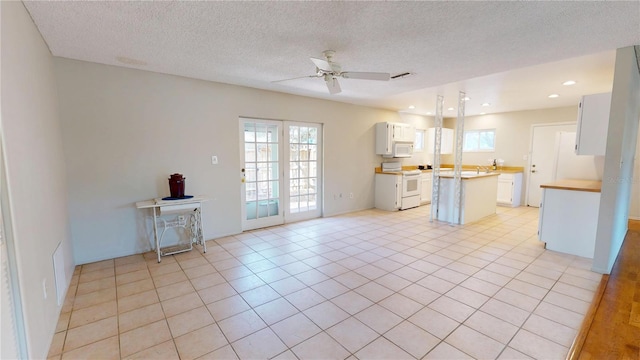 kitchen with ceiling fan, white appliances, a kitchen island, white cabinetry, and light countertops