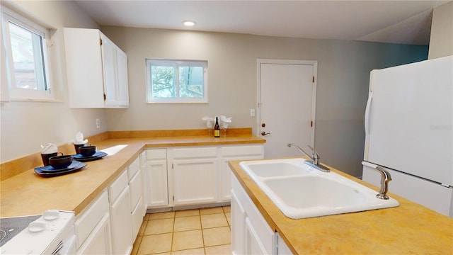 kitchen featuring plenty of natural light, light tile patterned flooring, a sink, and freestanding refrigerator