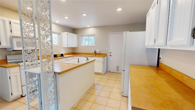 kitchen with light tile patterned floors, white appliances, white cabinets, light countertops, and a sink