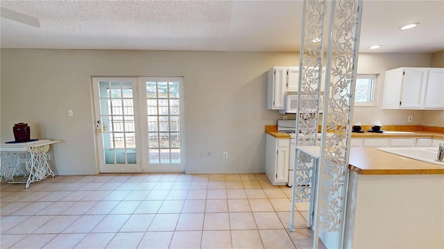 kitchen featuring light tile patterned floors, light countertops, white microwave, and white cabinets