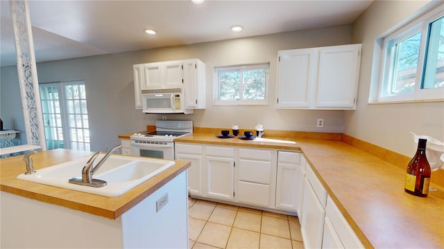 kitchen featuring white cabinetry, white appliances, a healthy amount of sunlight, and light tile patterned flooring