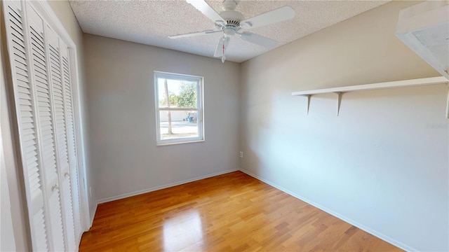 unfurnished bedroom with a textured ceiling, a ceiling fan, baseboards, a closet, and light wood finished floors