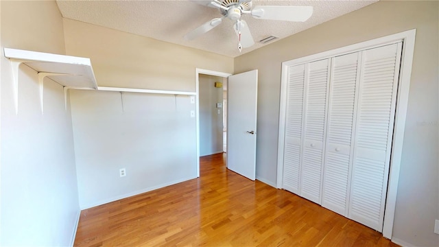 unfurnished bedroom featuring visible vents, ceiling fan, wood finished floors, a textured ceiling, and a closet