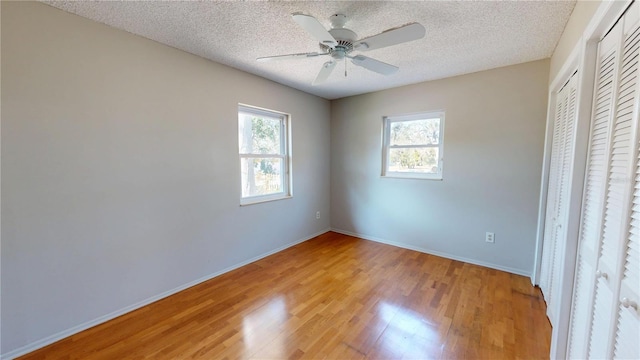 unfurnished bedroom with light wood finished floors, baseboards, and a textured ceiling