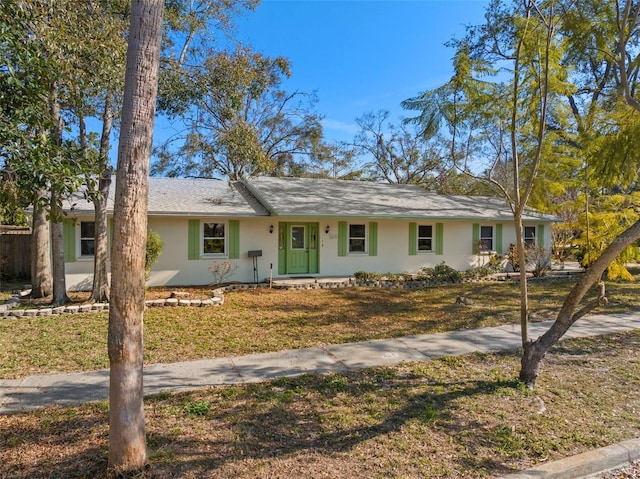 ranch-style home featuring a front lawn and stucco siding