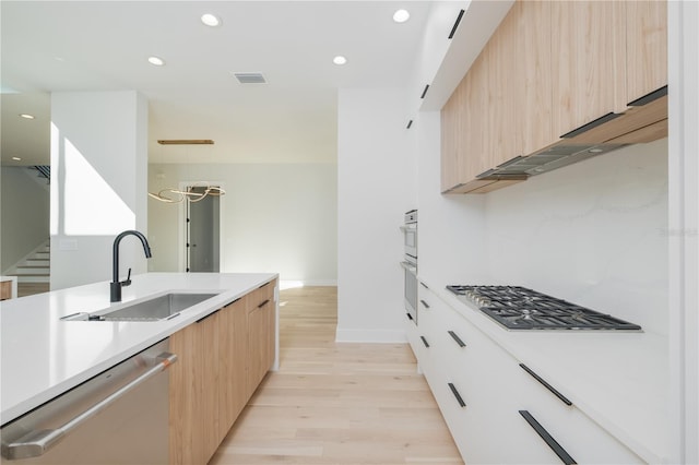 kitchen with stainless steel appliances, sink, light hardwood / wood-style flooring, and light brown cabinets