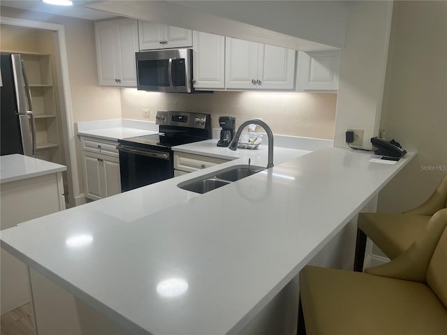 kitchen with appliances with stainless steel finishes, white cabinetry, sink, and kitchen peninsula